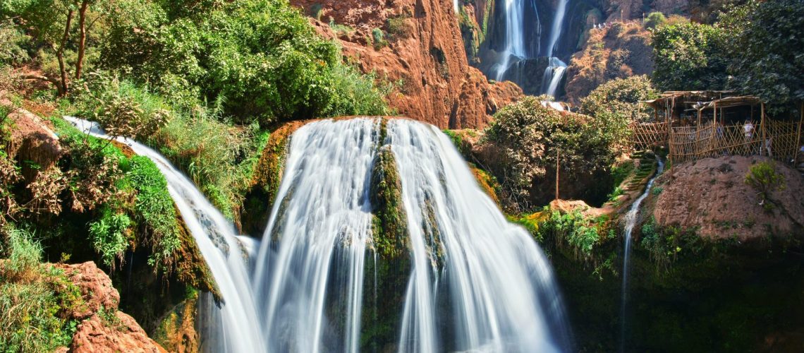 Ouzoud Waterfalls tumbling into a turquoise pool surrounded by olive trees and lush greenery